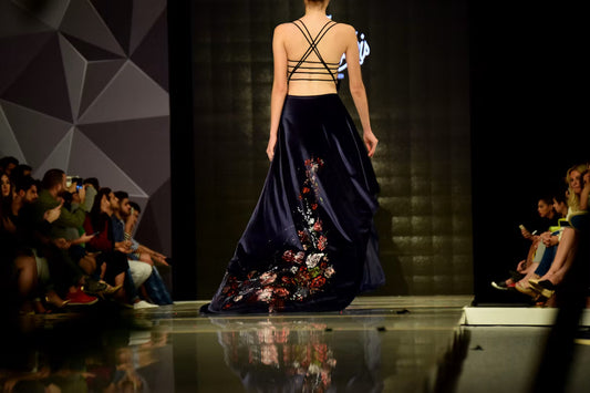 Modelo de costas na passarela com vestido longo de veludo azul-marinho bordado com flores
